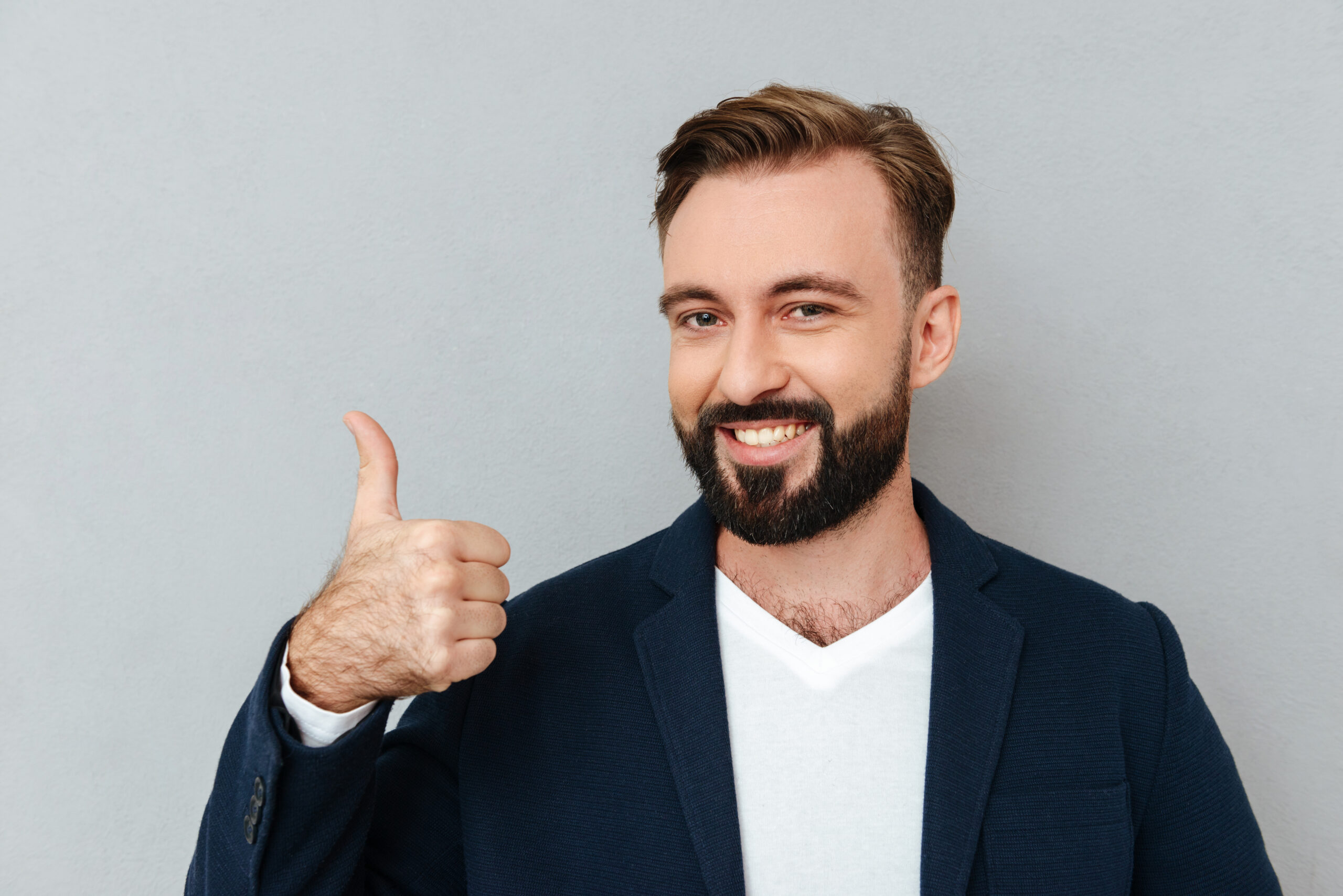 A confident man in a navy blazer gives a thumbs-up with a bright smile, representing trust and excellence in facility management.