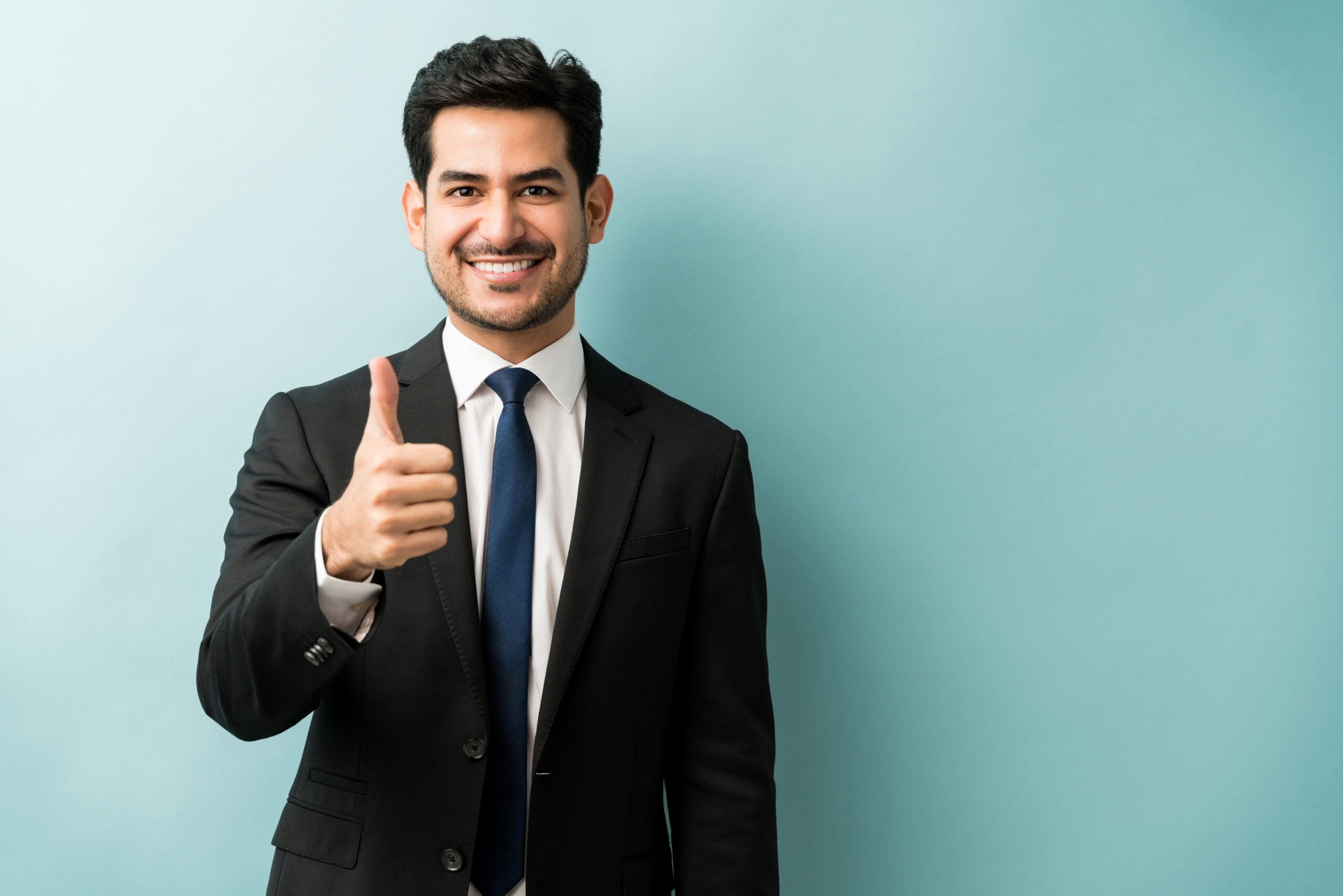 A smiling man in a black suit gives a thumbs-up, symbolizing trust and excellence in facility management services.