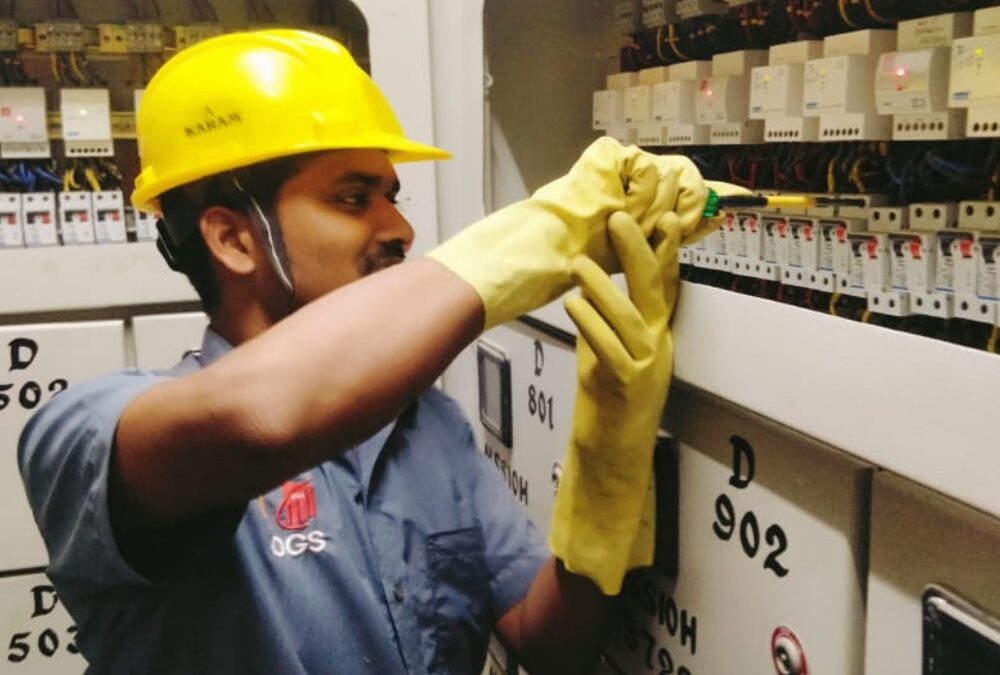 Technician working on electrical panel at OGS, one of the top electrical facility management companies in Bangalore.