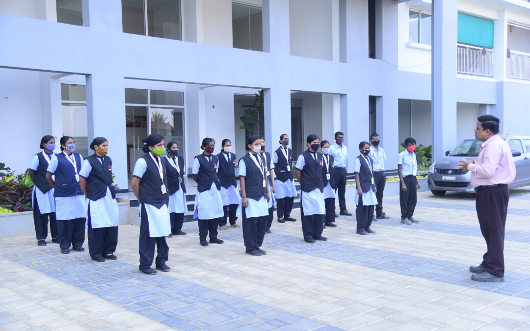 Employees receiving instructions outdoors, wearing uniforms and masks, showcasing facility management services in Bangalore.