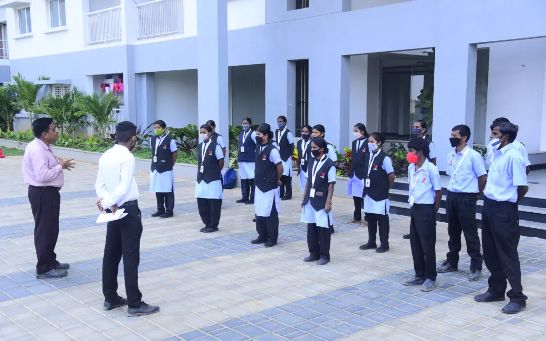 Employees of one of the top facility management companies in Bangalore stand in uniform during a briefing session outdoors.