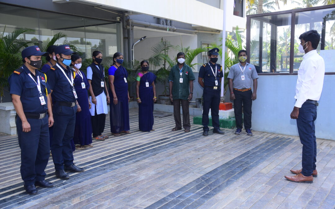 A team of uniformed facility management staff in Bangalore stands in formation outdoors, receiving instructions from a supervisor.